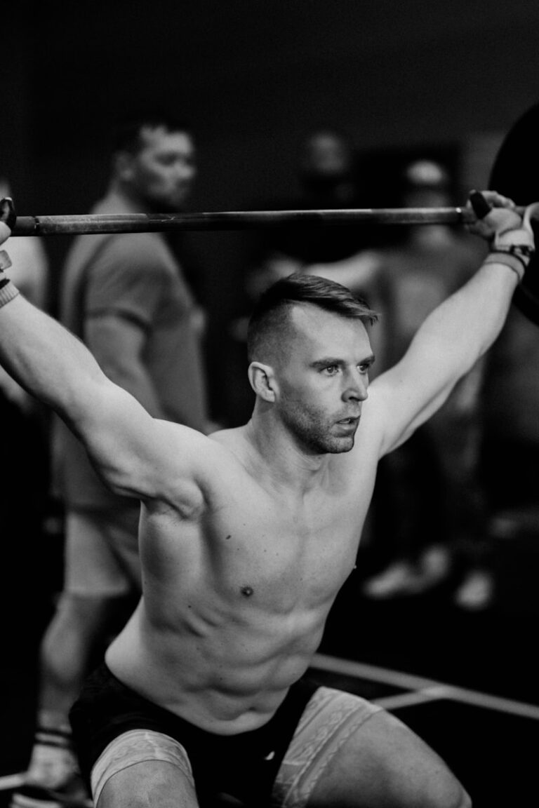 a shirtless man holding a barbell in his hands